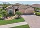 Aerial view of the home showcasing lush landscaping, stone accents, and a brick driveway at 13587 Vancanza Dr, Venice, FL 34293