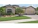 Charming front exterior showcasing lush landscaping, stone accents, and a well-maintained lawn at 13587 Vancanza Dr, Venice, FL 34293
