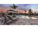 Relaxing community pool and lounge area with palm trees at sunset at 15165 Cuzcorro Ct, Nokomis, FL 34275