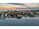 An aerial showcases waterfront views, boat docks, city skyline, and stunning sunset, perfect for coastal living at 1643 Stanford Ln, Sarasota, FL 34231