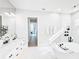 Bright bathroom featuring a soaking tub, double vanity, and white marble tiling at 1643 Stanford Ln, Sarasota, FL 34231