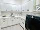 Well-organized laundry room featuring white cabinetry, quartz countertops, and modern appliances at 1643 Stanford Ln, Sarasota, FL 34231