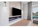 Modern living room features an electric fireplace with blue glass, a large TV, and access to the balcony at 1643 Stanford Ln, Sarasota, FL 34231