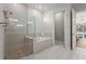 Bright bathroom featuring a soaking tub and glass-enclosed shower with neutral color scheme and tile floors at 16434 Slate Pl, Bradenton, FL 34211