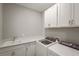 Functional laundry room with white cabinets, countertops, sink, and modern washer and dryer at 16434 Slate Pl, Bradenton, FL 34211