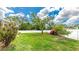 Large grassy backyard enclosed with a white privacy fence and mature trees at 1667 Oakland Rd, North Port, FL 34286