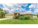 Charming exterior featuring a manicured lawn, beautiful landscaping, and an attached two-car garage at 1667 Oakland Rd, North Port, FL 34286