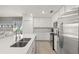 Well-lit kitchen featuring white cabinets, stainless steel appliances, and a view of the living space at 17510 Gawthrop Dr # 208, Bradenton, FL 34211