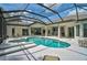 The screened-in pool has a spa and overlooks the home's interior through glass doors at 2111 Muskogee Trl, Nokomis, FL 34275