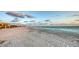 Expansive beach view, featuring a serene sandy shore, gentle waves, and distant buildings under a cloudy sky at 2185 Gulf Of Mexico Dr # 243, Longboat Key, FL 34228