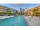 Beautiful condo complex with a stunning pool, lounge chairs, and tropical landscaping under a clear blue sky at 2185 Gulf Of Mexico Dr # 243, Longboat Key, FL 34228