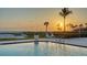 Inviting pool view showcases a beautiful sunset, ocean view, poolside seating, and lush landscaping at 2185 Gulf Of Mexico Dr # 243, Longboat Key, FL 34228