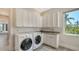 Well-lit laundry room with a large sink, white cabinets, and washer and dryer at 244 Cedar Park Cir, Sarasota, FL 34242