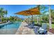 Relaxing pool area with lounge chairs, a large sun umbrella, and beautiful landscaping for outdoor enjoyment at 244 Cedar Park Cir, Sarasota, FL 34242
