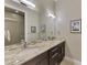 Bathroom featuring double sinks, granite countertops, framed mirrors, and a tiled shower at 24705 83Rd E Ave, Myakka City, FL 34251