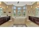 Elegant bathroom featuring a corner tub with surrounding windows, double vanity sinks, and tiled floor at 24705 83Rd E Ave, Myakka City, FL 34251