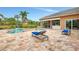 Inviting pool and spa area with travertine tile, outdoor kitchen, and covered patio with blue cushions at 24705 83Rd E Ave, Myakka City, FL 34251