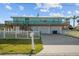 Inviting two-story coastal home with a spacious deck, white picket fence, and large driveway at 3416 Crape Myrtle Dr, Hernando Beach, FL 34607