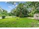 Spacious backyard with lush green grass, palm trees, and a charming fire pit at 3608 Water St, Ellenton, FL 34222