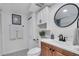 Bathroom with white cabinet, black hardware, round mirror, and black and white tiled floor at 3608 Water St, Ellenton, FL 34222
