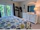 A main bedroom with a decorative bedspread, white dresser, and balcony access, offering a bright and serene retreat at 3744 Lake Bayshore Dr # K-503, Bradenton, FL 34205