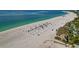 Beautiful beachfront property with rows of beach chairs, umbrellas, and swaying palm trees near the turquoise water at 4307 Camino Real, Sarasota, FL 34231