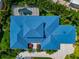 A striking aerial view of the meticulously landscaped home with a vibrant blue roof and circular driveway at 4307 Camino Real, Sarasota, FL 34231
