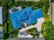 Stunning aerial view of a house with a pool surrounded by lush green lawns, blue roof and mature trees at 4307 Camino Real, Sarasota, FL 34231
