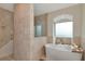Spa-like bathroom showcasing a modern soaking tub with travertine tiled walls and natural light at 4307 Camino Real, Sarasota, FL 34231