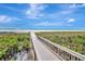 Picturesque beach access with a wooden walkway leading to the ocean and lush greenery surrounding at 4307 Camino Real, Sarasota, FL 34231