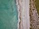Aerial view of the turquoise ocean water gently lapping onto a pristine white sand beach at 4307 Camino Real, Sarasota, FL 34231