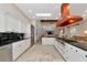 Bright, airy kitchen featuring white cabinets, black countertops, stainless steel appliances, and copper range hood at 4307 Camino Real, Sarasota, FL 34231
