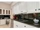 Kitchen features white cabinets, black countertop, stainless steel appliances, and black backsplash at 4307 Camino Real, Sarasota, FL 34231