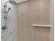 Close up of shower with marble accent wall and wood toned wall with shower head at 4307 Camino Real, Sarasota, FL 34231
