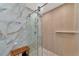 Elegant shower with glass doors, marble accents, and a wood-look tiled wall at 4307 Camino Real, Sarasota, FL 34231