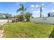 A backyard featuring a well-maintained lawn, privacy fence, mature trees, and an open wooden pavilion at 4717 Lemon Bay Dr, Venice, FL 34293