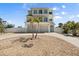 Coastal home featuring a garage, gravel landscaping, and two palm trees in the front yard at 4717 Lemon Bay Dr, Venice, FL 34293
