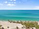 A beautiful ocean view with a sandy beach lined with lush palm trees, under a clear blue sky at 4717 Lemon Bay Dr, Venice, FL 34293