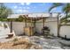 Outdoor kitchen space with a grill and bar surrounded by lush greenery in backyard at 4717 Lemon Bay Dr, Venice, FL 34293