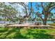 Beautiful waterfront backyard featuring a wooden deck with seating surrounded by mature trees and green grass at 5377 Palos Verdes Dr, Sarasota, FL 34231