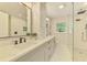 Bright bathroom boasts dual sinks, white marble counters, gray cabinets, and a glass-enclosed shower with marble tile at 5377 Palos Verdes Dr, Sarasota, FL 34231