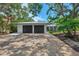 Beautiful home featuring a two-car garage with a metal roof and a spacious driveway, surrounded by mature trees at 5377 Palos Verdes Dr, Sarasota, FL 34231