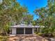 Beautiful home featuring a two-car garage with a metal roof and a spacious driveway, surrounded by mature trees at 5377 Palos Verdes Dr, Sarasota, FL 34231