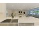 Modern kitchen featuring a stainless steel sink, marble countertops, and seamless transition to a bright living space at 5377 Palos Verdes Dr, Sarasota, FL 34231