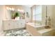 The bathroom features a dual vanity, soaking tub, glass-enclosed shower, and plenty of natural light at 5684 Blue Reef Place, Nokomis, FL 34275
