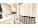 Bright bathroom featuring a white vanity, framed art, and shower with a striped curtain at 5684 Blue Reef Place, Nokomis, FL 34275
