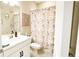 This bathroom features floral decorations and a shower curtain, vanity, and a neutral-colored mat at 5684 Blue Reef Place, Nokomis, FL 34275