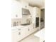 Well-lit kitchen with sleek white cabinetry, stainless steel appliances, and modern gas cooktop at 5684 Blue Reef Place, Nokomis, FL 34275