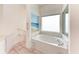 Bright bathroom featuring a soaking tub with marble surround and large window at 585 Khyber Ln, Venice, FL 34293