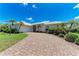 Beautiful single-story home with a brick driveway, well-manicured lawn, and tropical landscaping at 585 Khyber Ln, Venice, FL 34293